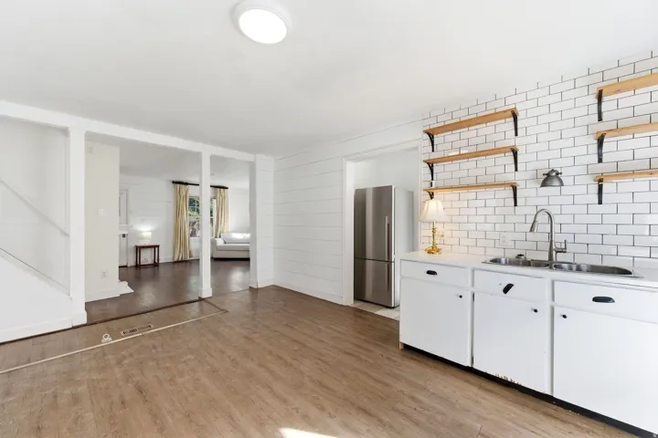Kitchen featuring light countertops, freestanding refrigerator, white cabinets, and open shelves