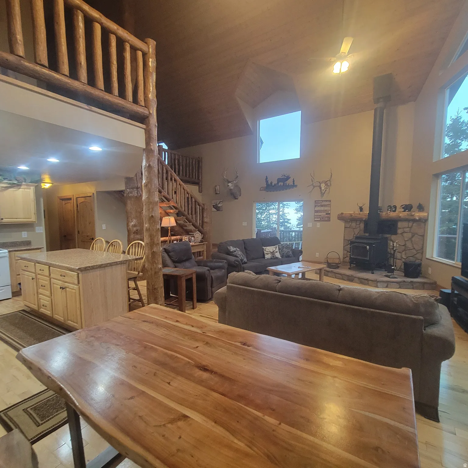 Dining area featuring a high ceiling, light wood-type flooring, and a wood stove
