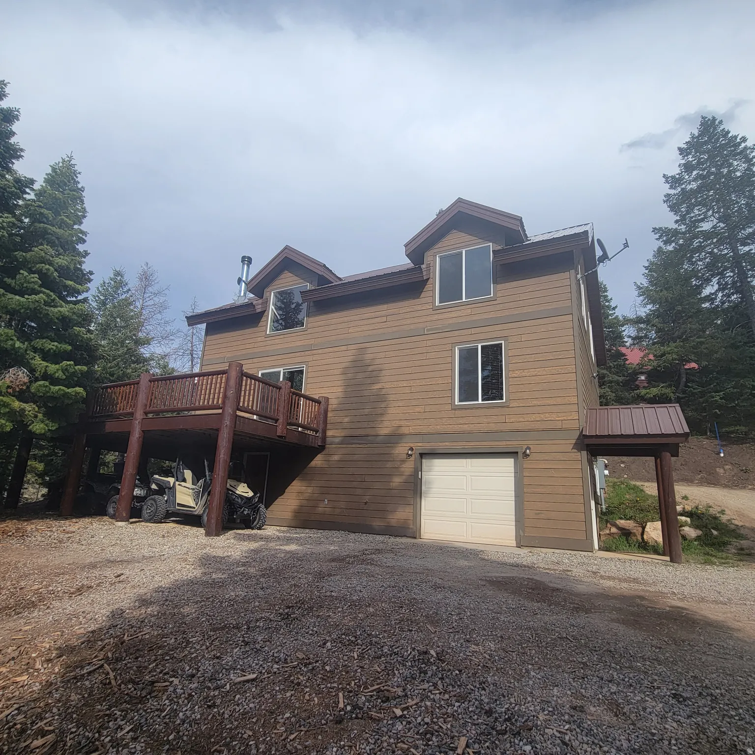 View of side of home with a garage, a wooden deck, and driveway