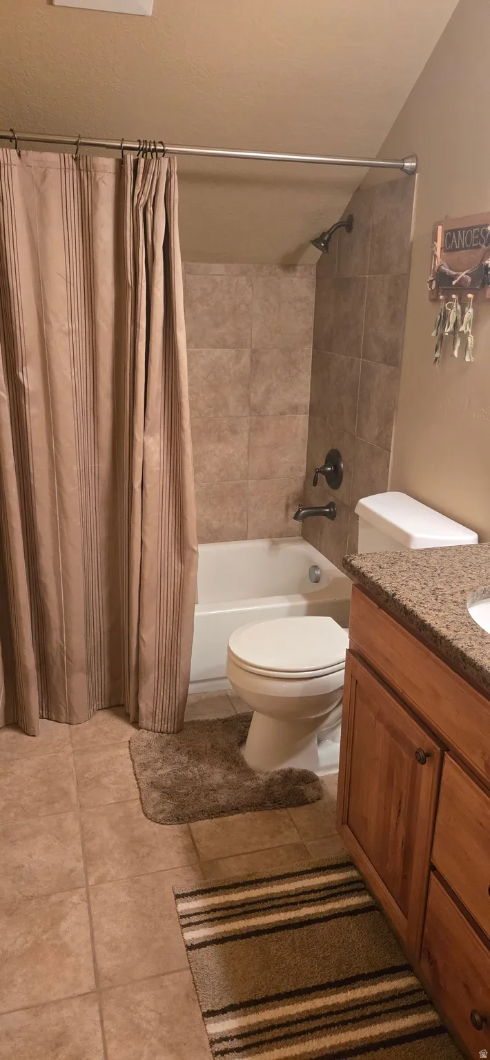 Bathroom featuring vanity, shower / bath combo, and light tile patterned flooring