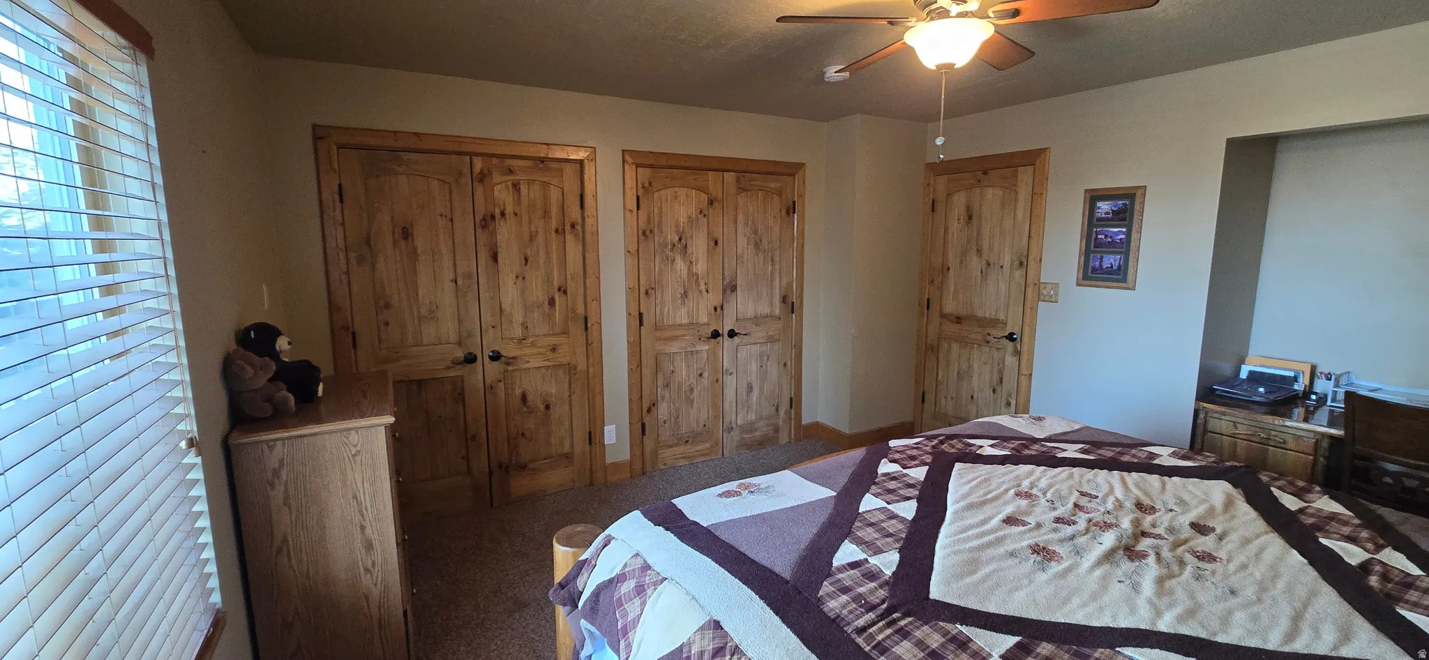 Carpeted bedroom with multiple closets and ceiling fan