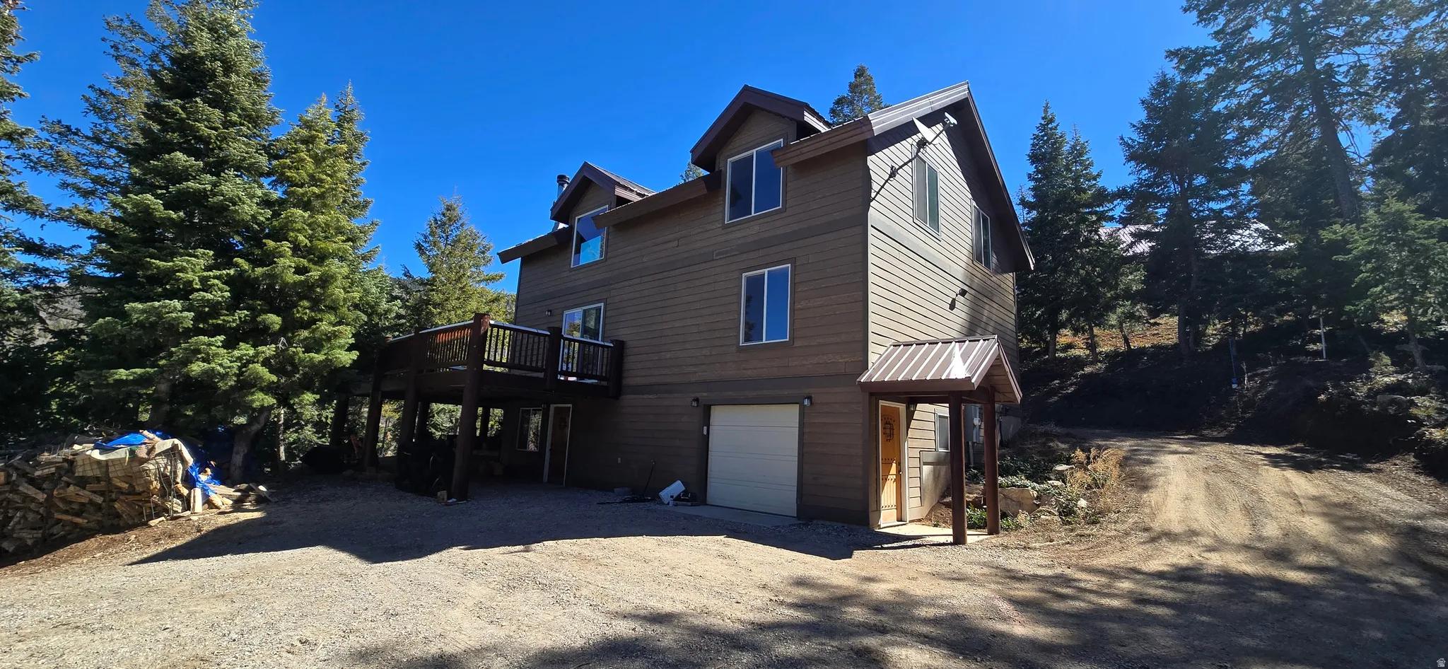 View of side of property with an attached garage, dirt driveway, and a deck
