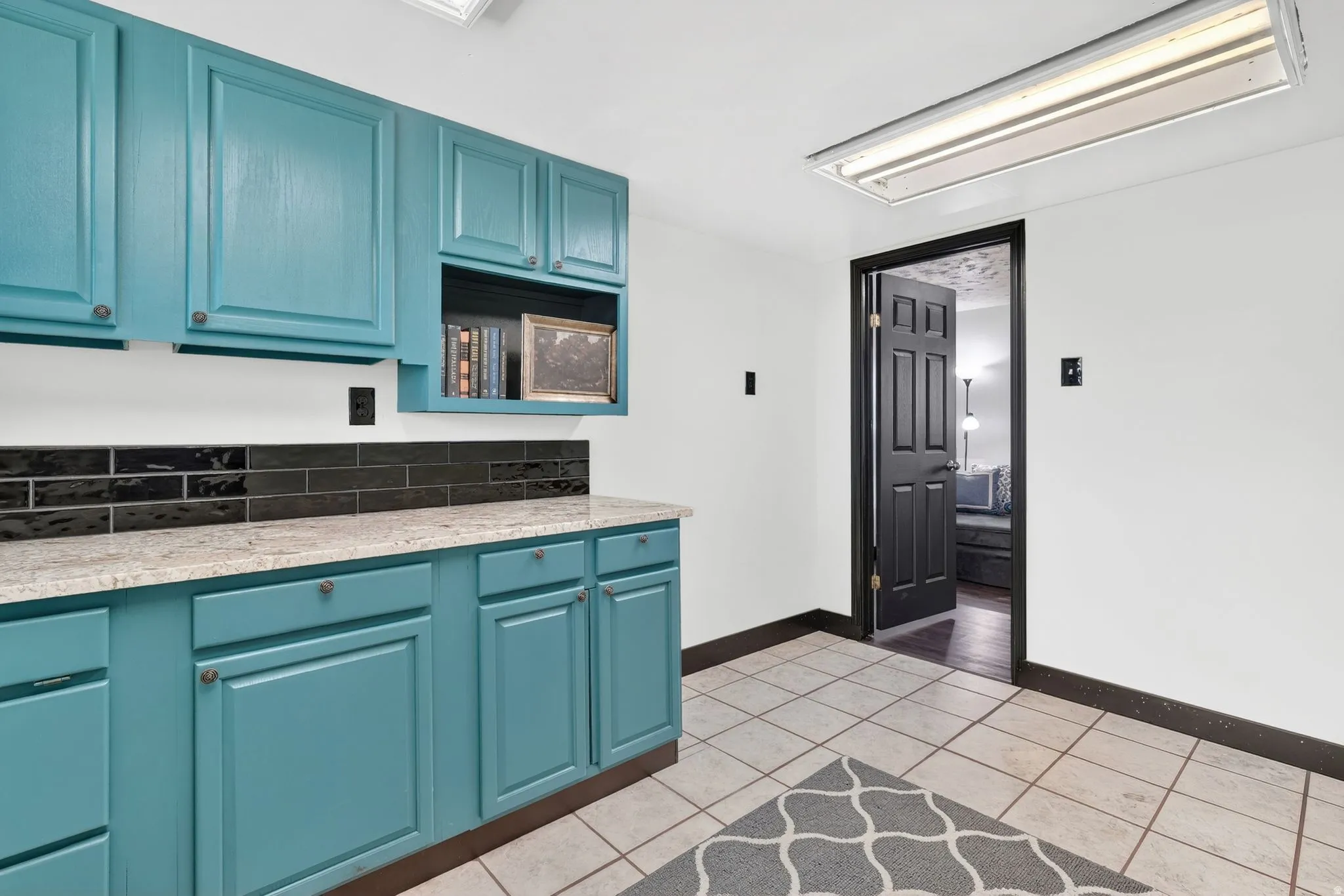 Kitchen with light tile patterned floors, blue cabinets, and light stone counters