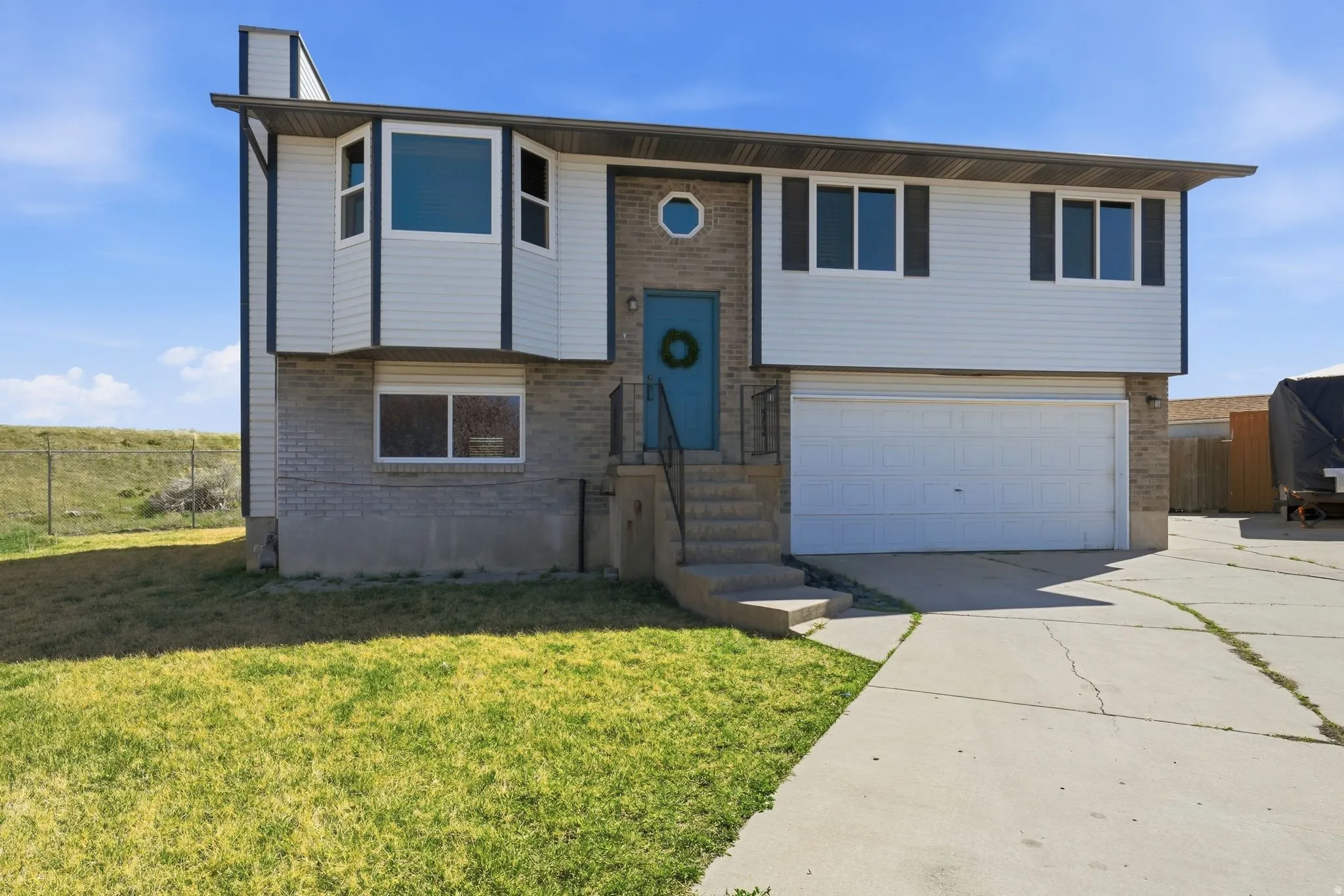 Raised ranch with brick siding, a garage, concrete driveway, and a chimney
