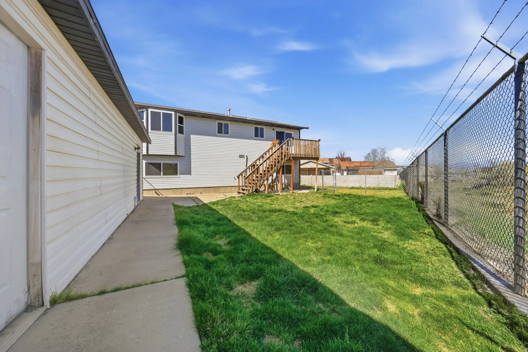 Fenced backyard with a wooden deck and a patio area