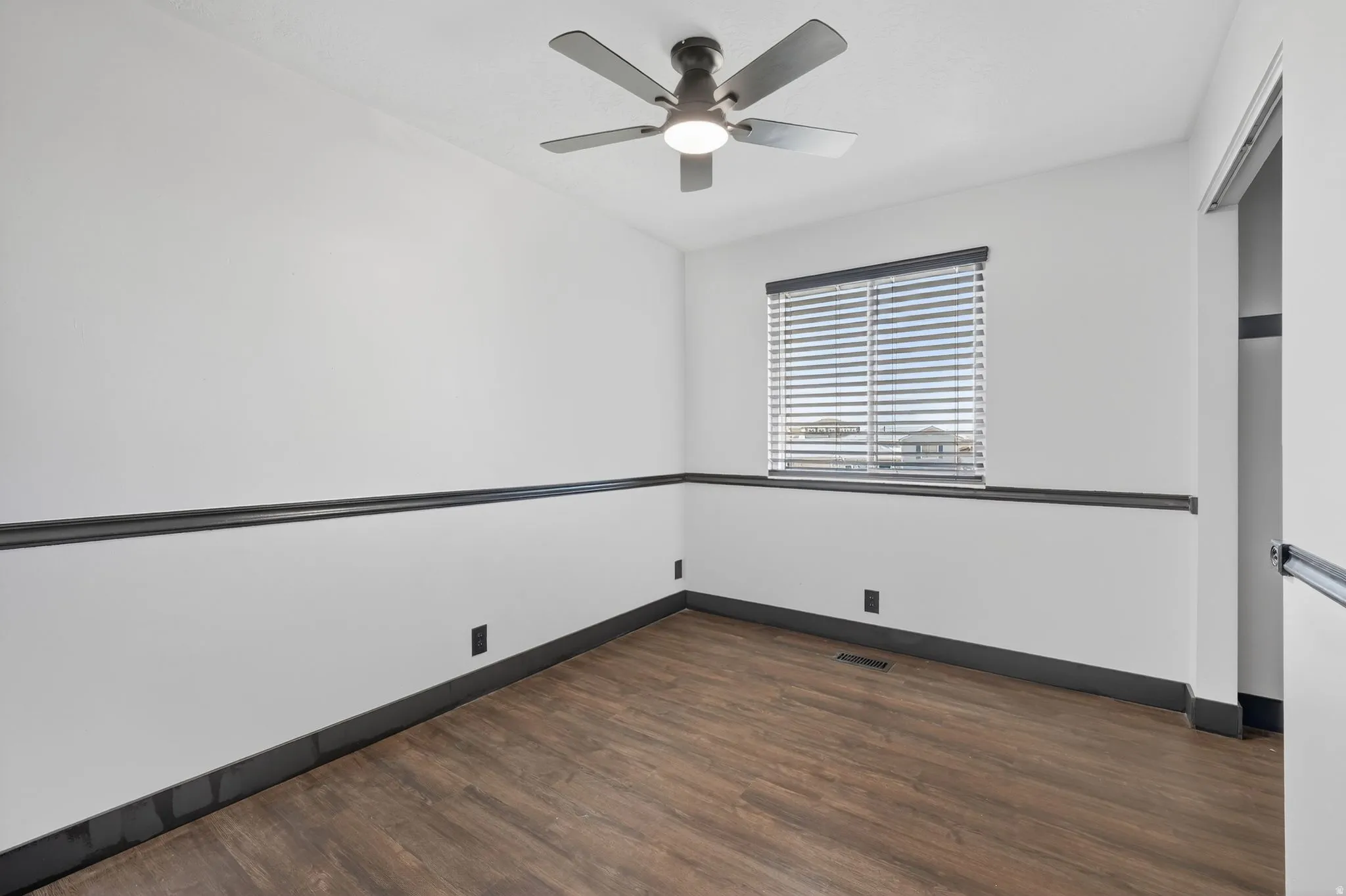 Empty room with dark wood-style floors and ceiling fan