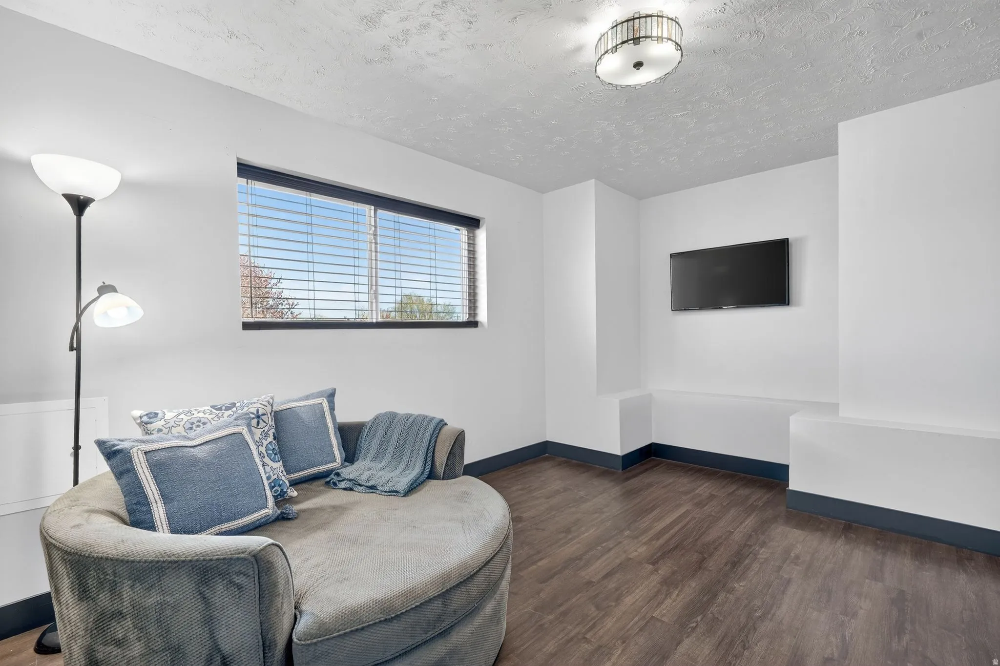 Sitting room with dark wood-type flooring and a textured ceiling