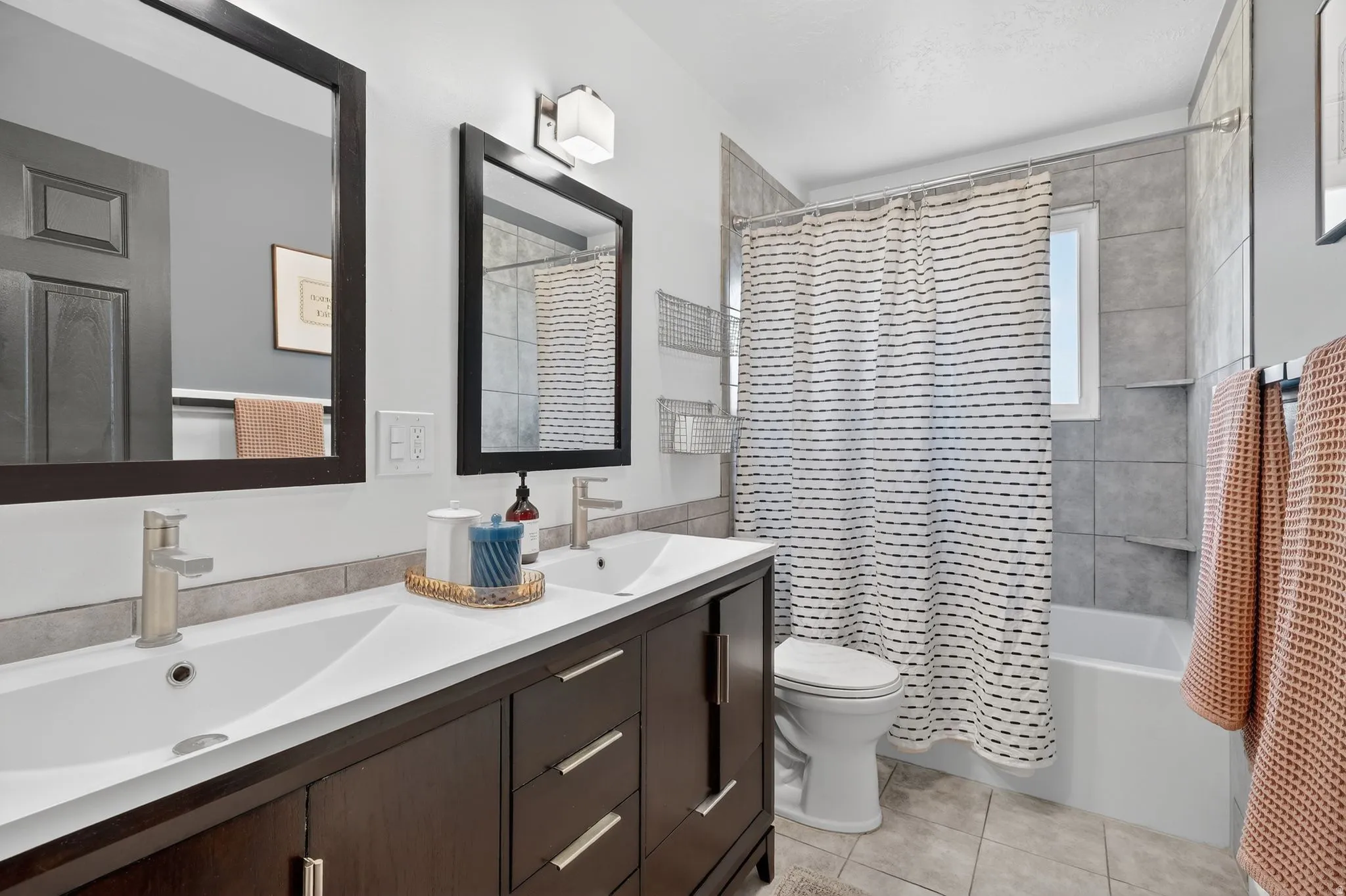Full bathroom with double vanity, shower / tub combo, and light tile patterned flooring