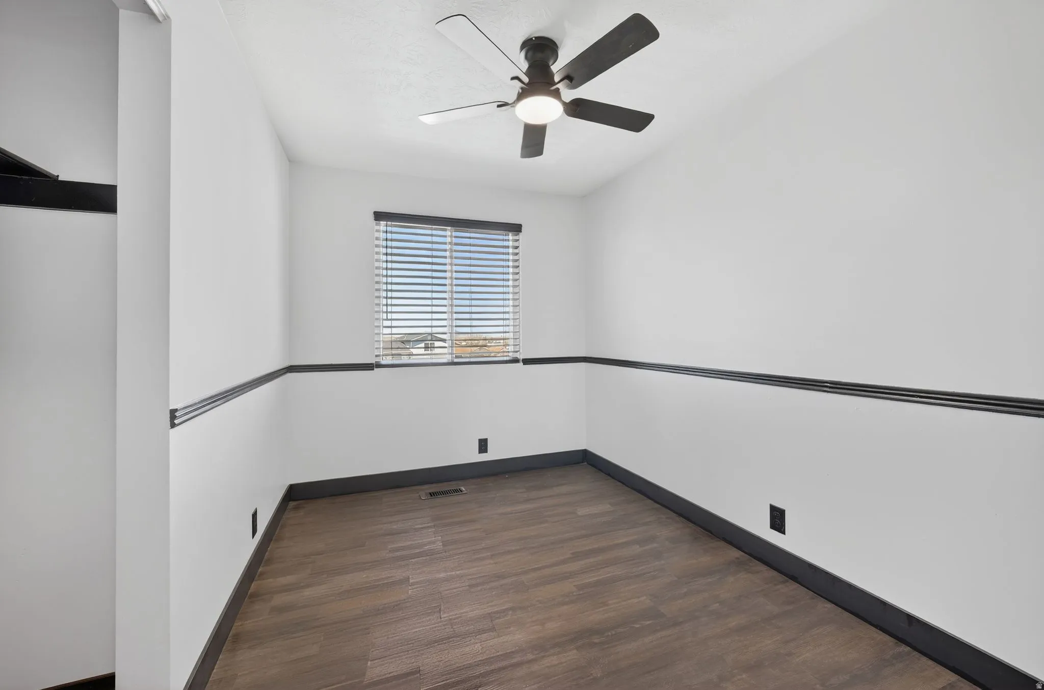 Unfurnished room featuring dark wood-type flooring and a ceiling fan