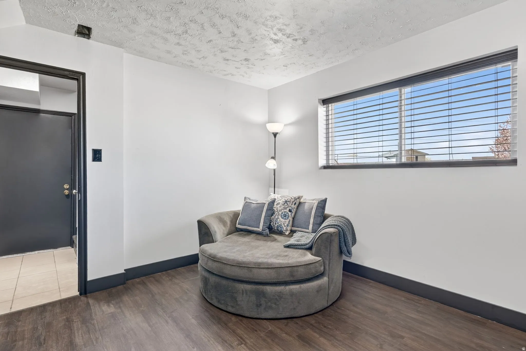 Sitting room with dark wood-type flooring and a textured ceiling