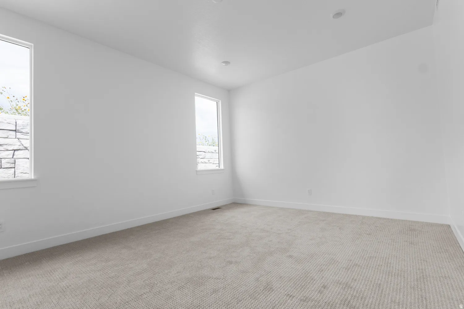 Spare room featuring light colored carpet and baseboards