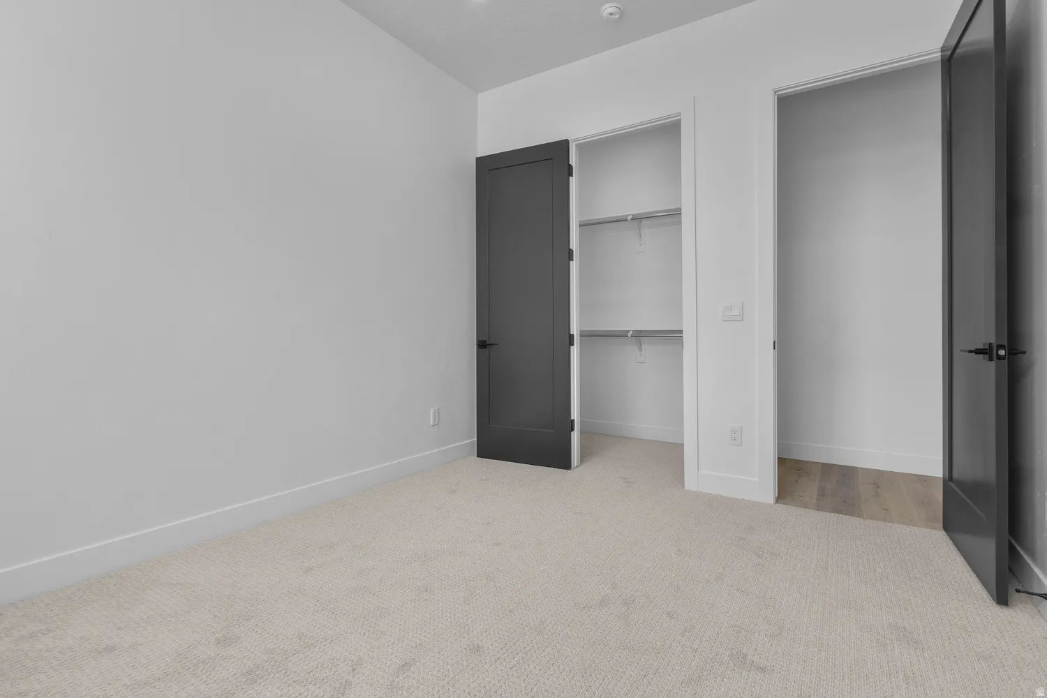 Unfurnished bedroom with light colored carpet and baseboards