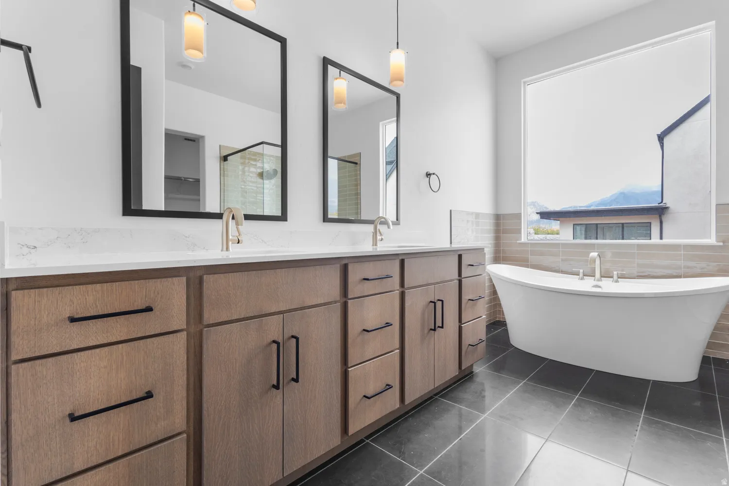 Bathroom featuring double vanity, a freestanding tub, tile walls, dark tile patterned floors, and a shower stall