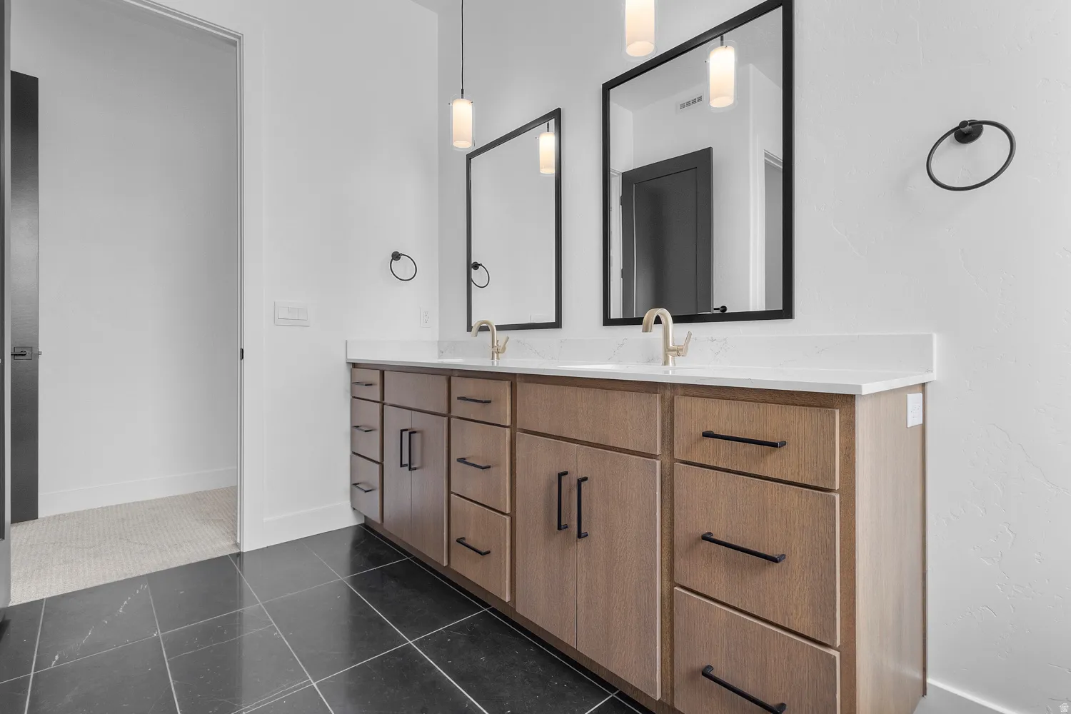 Full bath featuring double vanity and dark tile patterned flooring