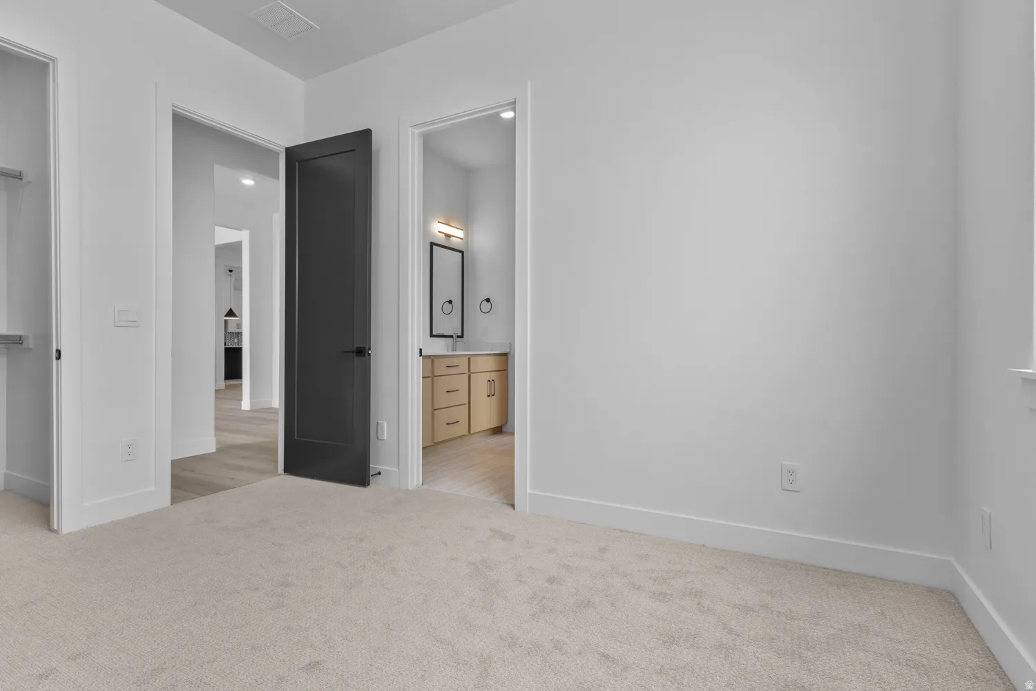 Unfurnished bedroom featuring light carpet and ensuite bathroom