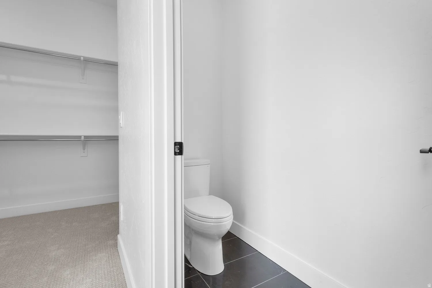 Bathroom with a walk in closet and dark tile patterned flooring