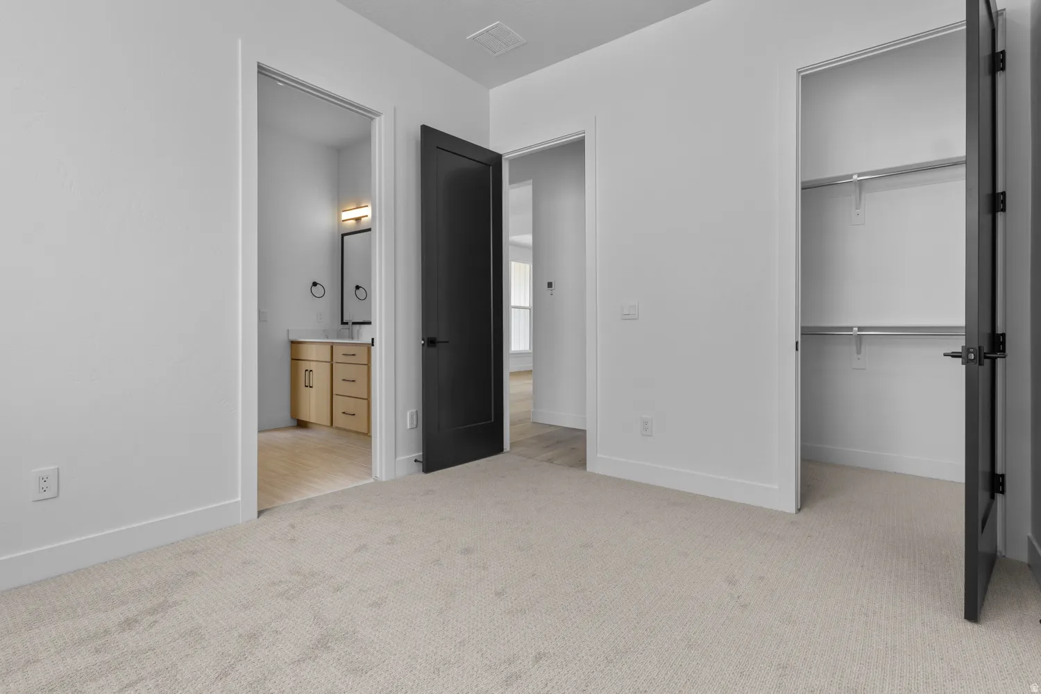 Unfurnished bedroom with light carpet and ensuite bath