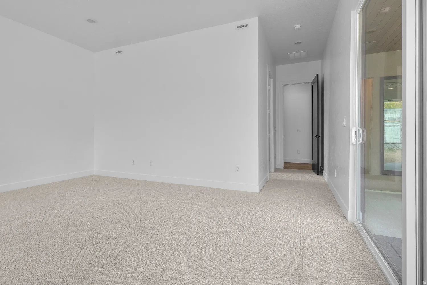 Unfurnished room featuring light carpet and baseboards