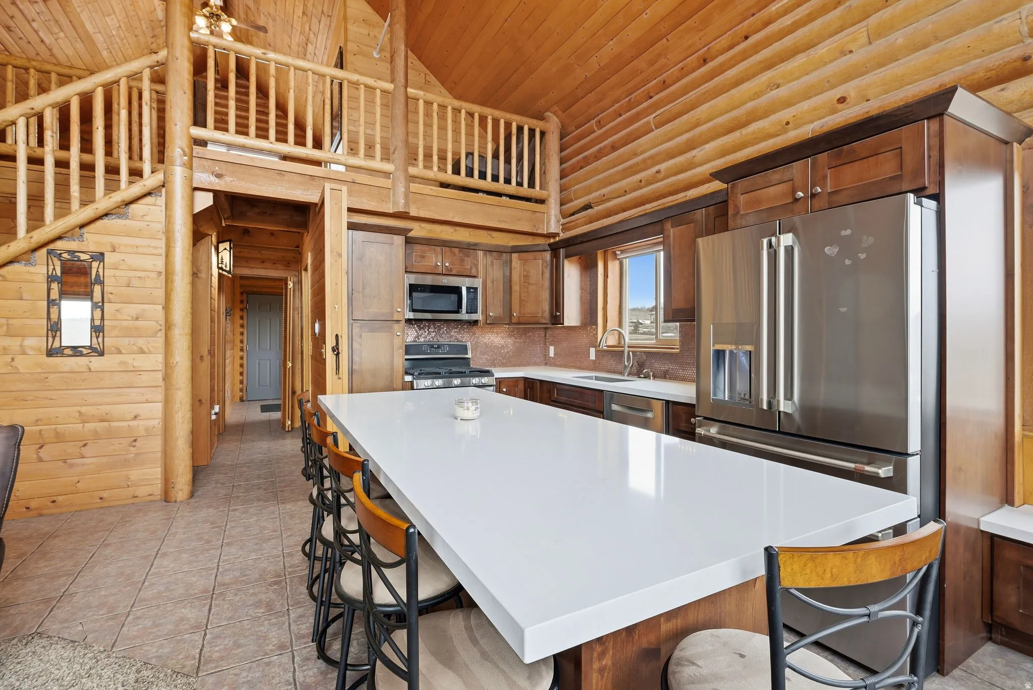 Kitchen with wooden walls, a breakfast bar, stainless steel appliances, a vaulted wooden ceiling, and backsplash