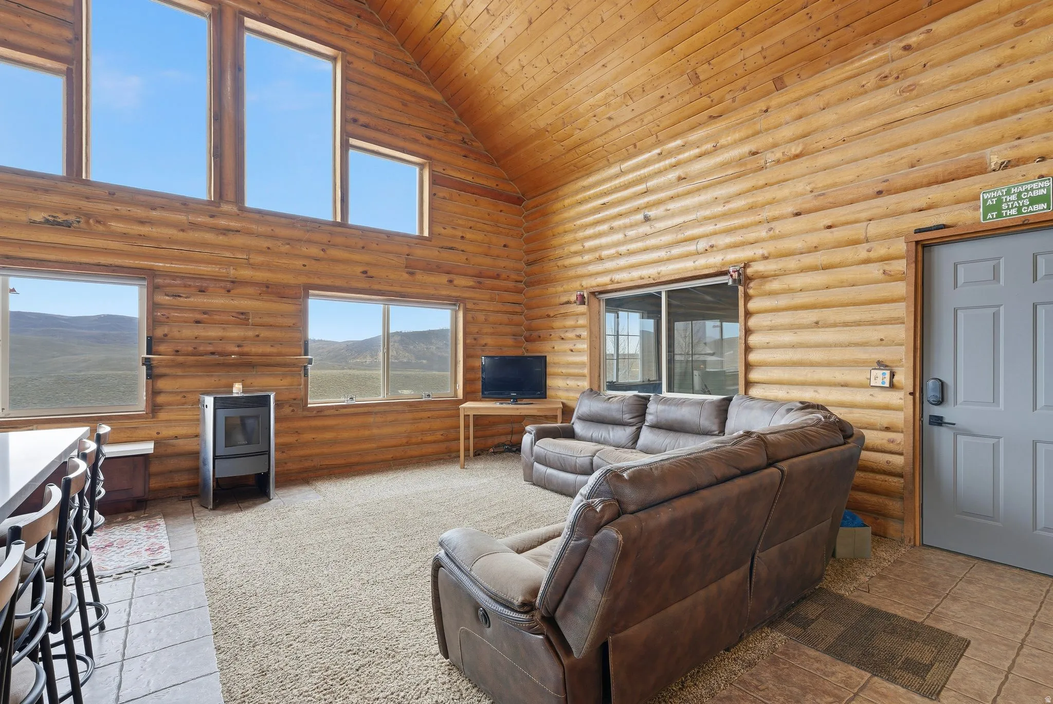 Living area with rustic walls, a vaulted wood ceiling, and light tile patterned floors