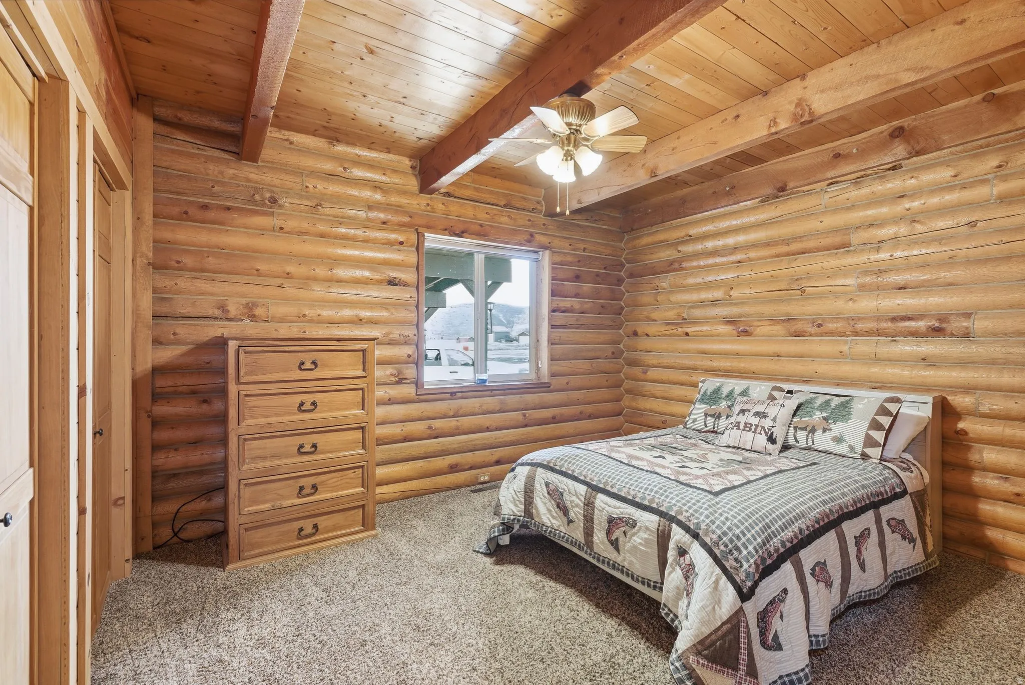 Bedroom featuring rustic walls, light colored carpet, a ceiling fan, a wood ceiling with exposed beams, and a closet