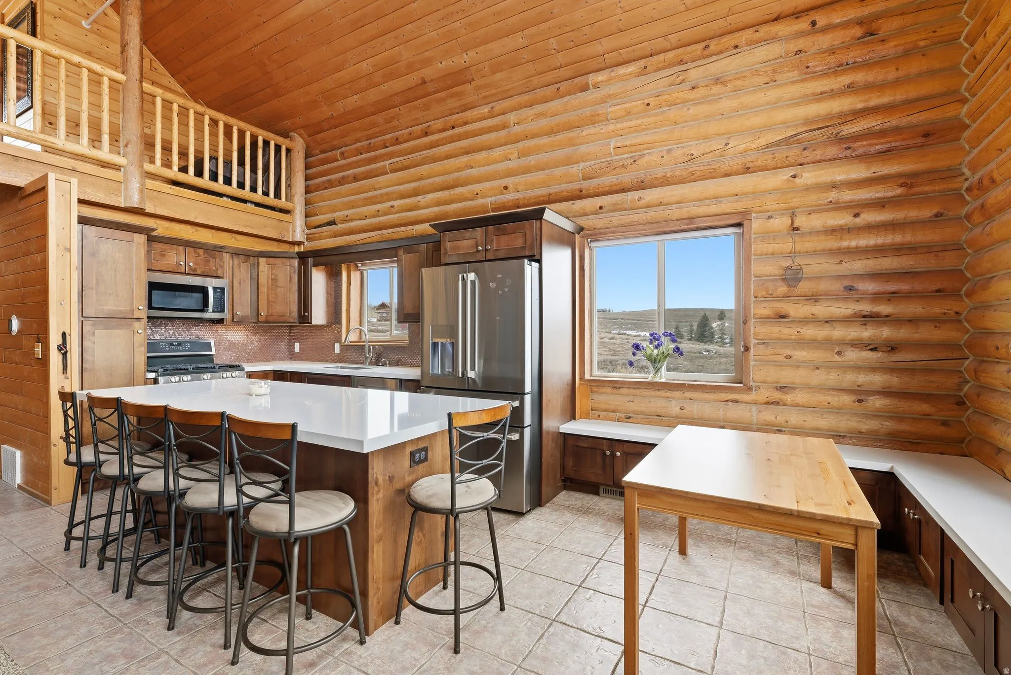 Kitchen with stainless steel appliances, a kitchen bar, log walls, a vaulted wood ceiling, and a center island