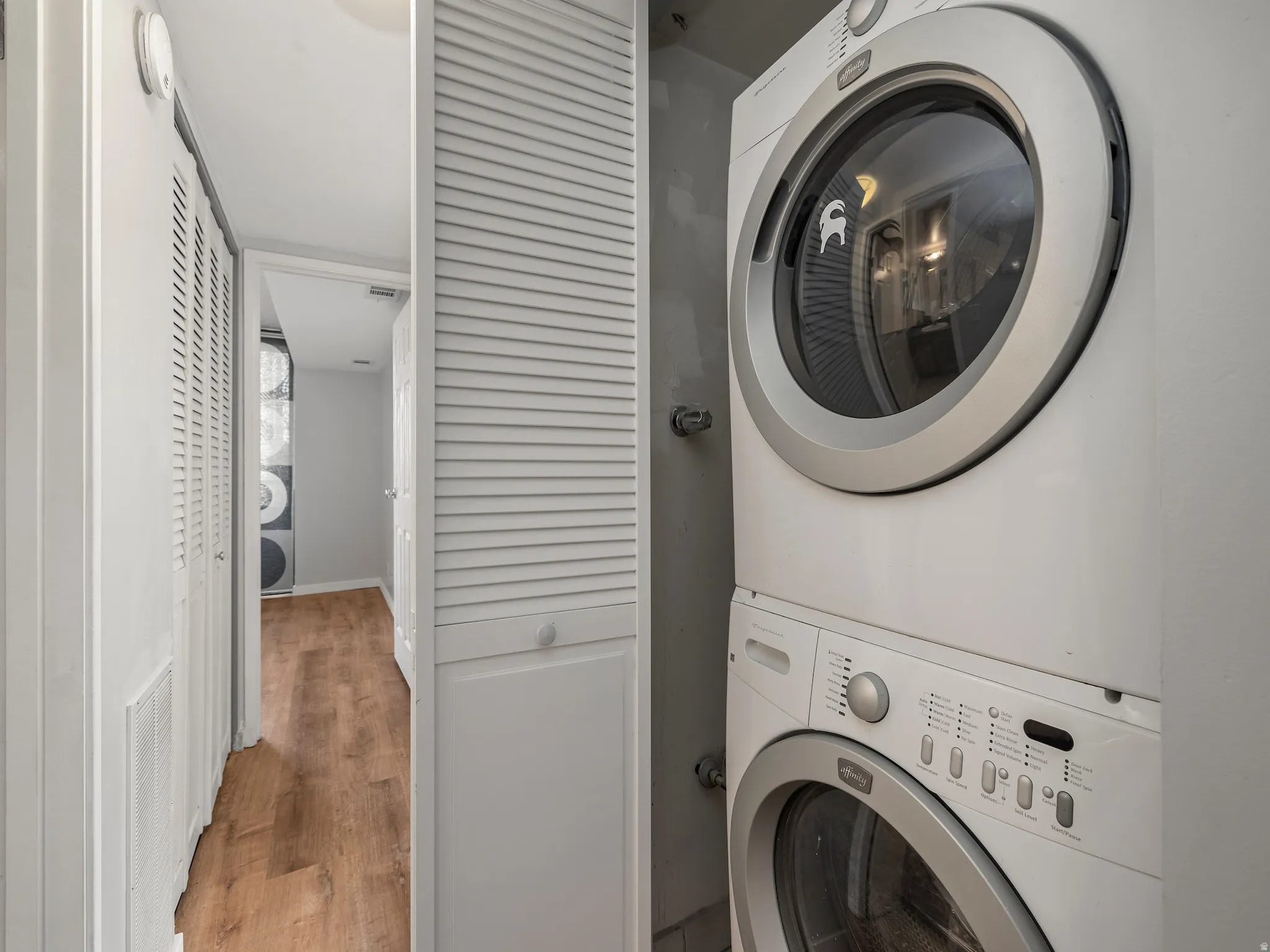 Laundry area featuring wood finished floors and stacked washer and clothes dryer