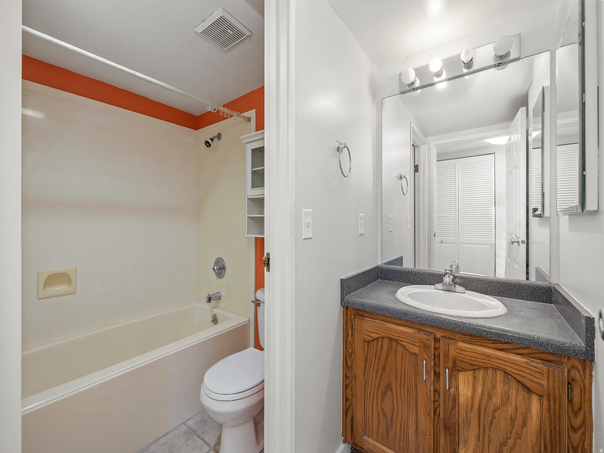 Bathroom with vanity, tub / shower combination, and light tile patterned floors