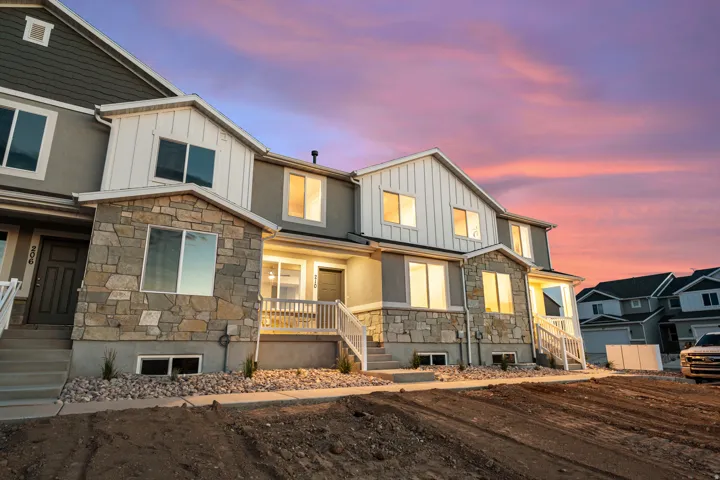 Modern townhome exterior featuring a combination of stone veneer, vertical white siding, and grey stucco