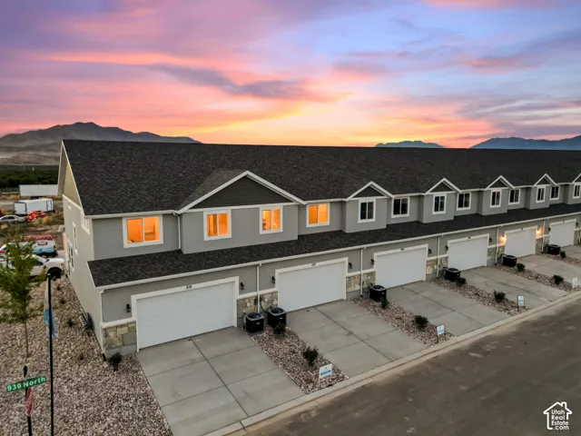 Modern townhome development featuring light gray stucco exteriors with stone veneer accents and dark shingled roofs