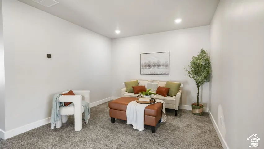 Carpeted interior space featuring recessed lighting, a white baseboard, and a wall-mounted control panel