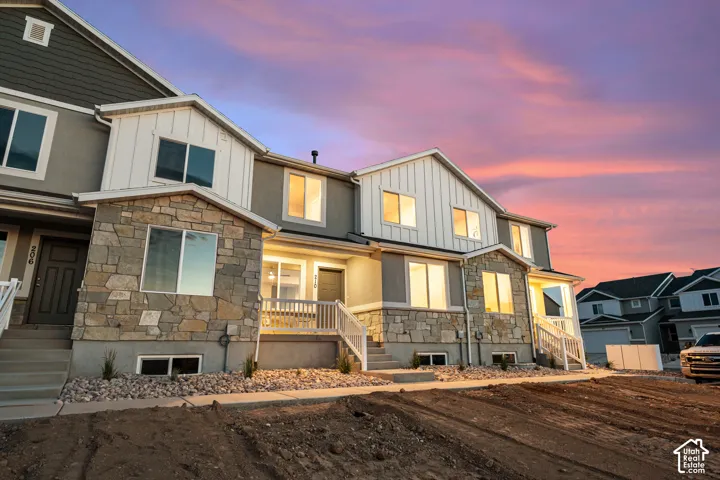 Modern townhome exterior featuring a combination of stone veneer, vertical white siding, and grey stucco