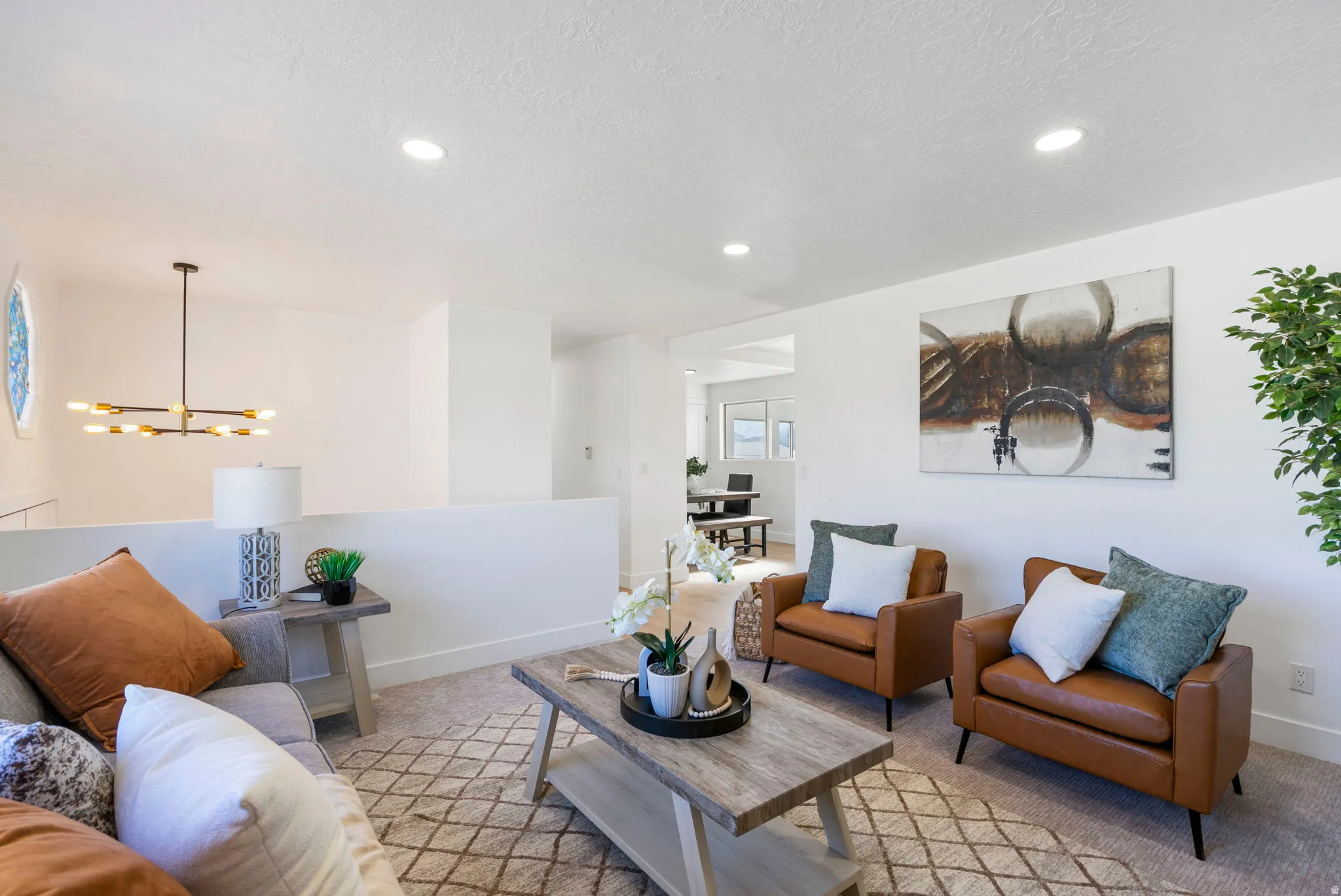 Living room with light colored carpet, a chandelier, and a textured ceiling