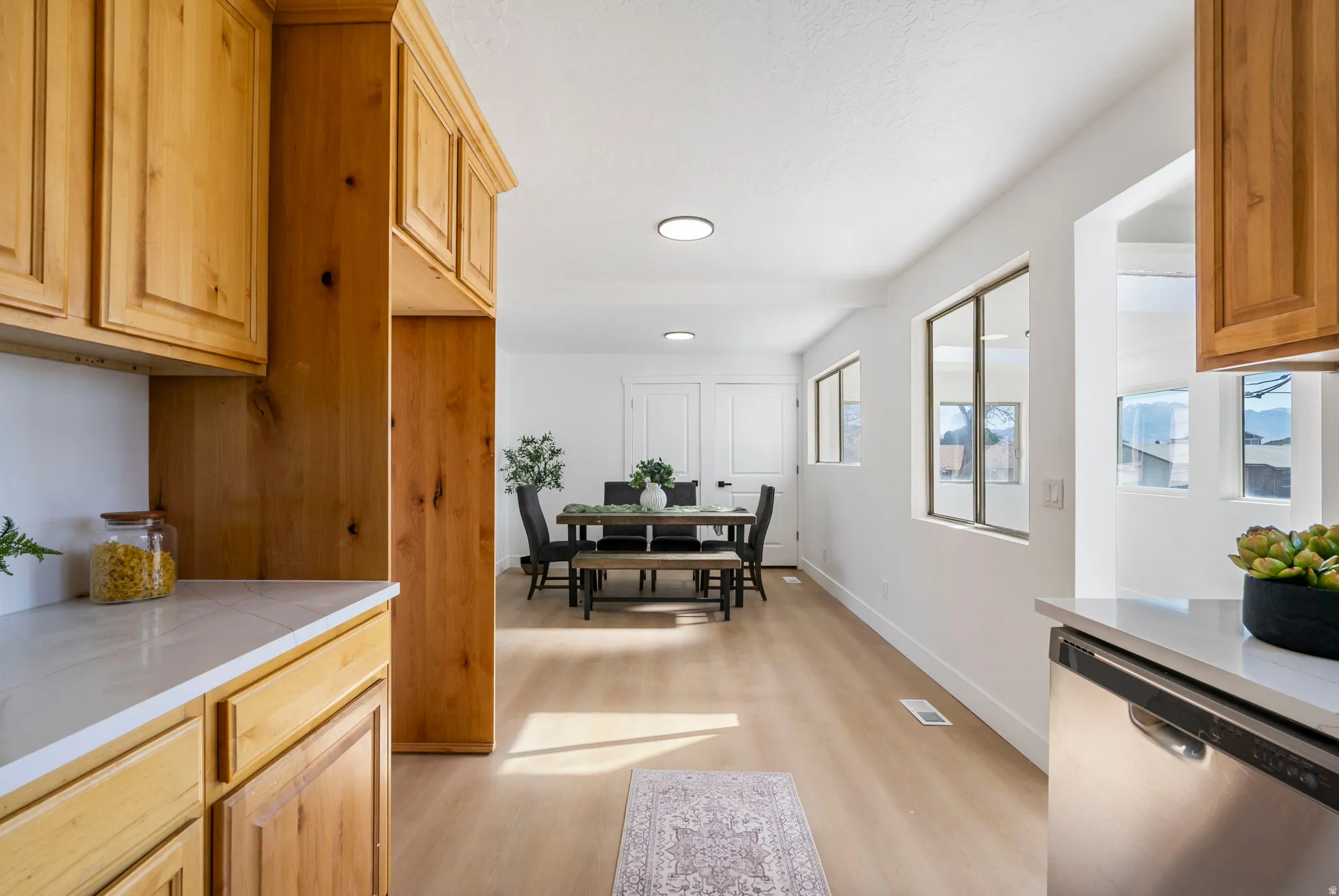 Kitchen with dishwasher, light wood-type flooring, light wood finish cabinets, and recessed lighting