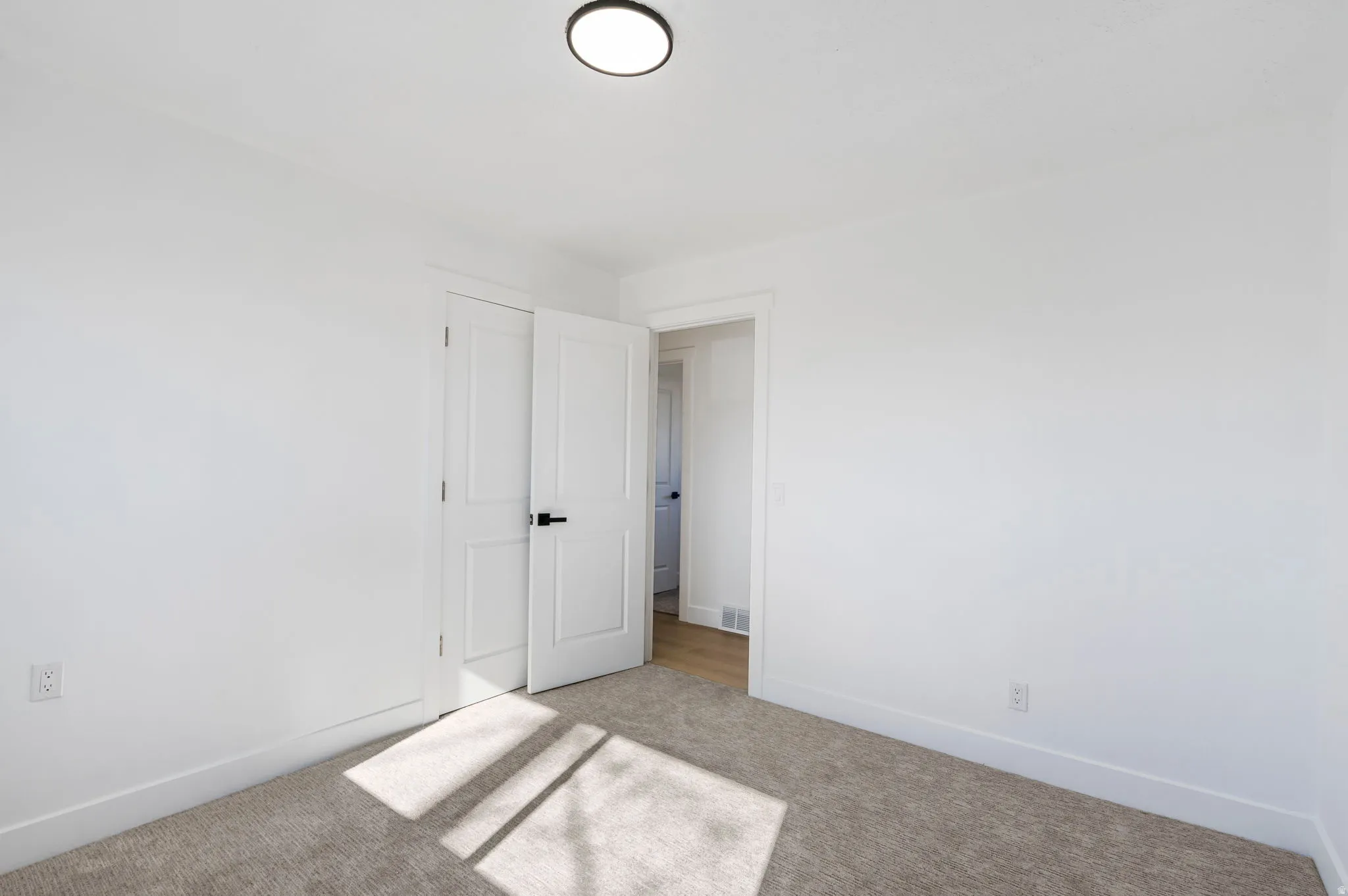 Unfurnished bedroom featuring light carpet and a closet