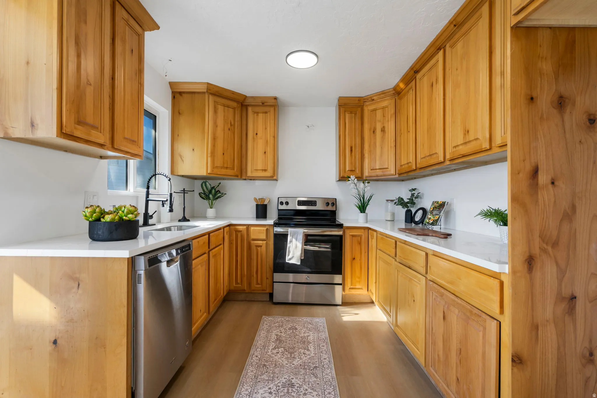 Kitchen featuring stainless steel appliances, light wood-style flooring, wood finish cabinets, and light stone counters