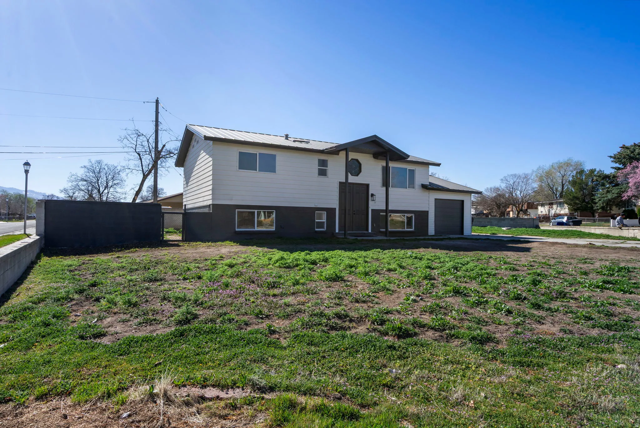 Split foyer home featuring an attached garage, driveway, and a metal roof