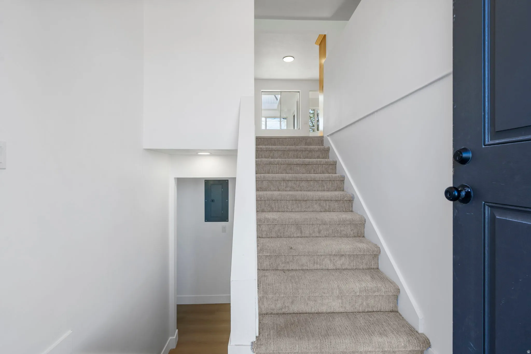 Staircase featuring wood finished floors, electric panel, and recessed lighting