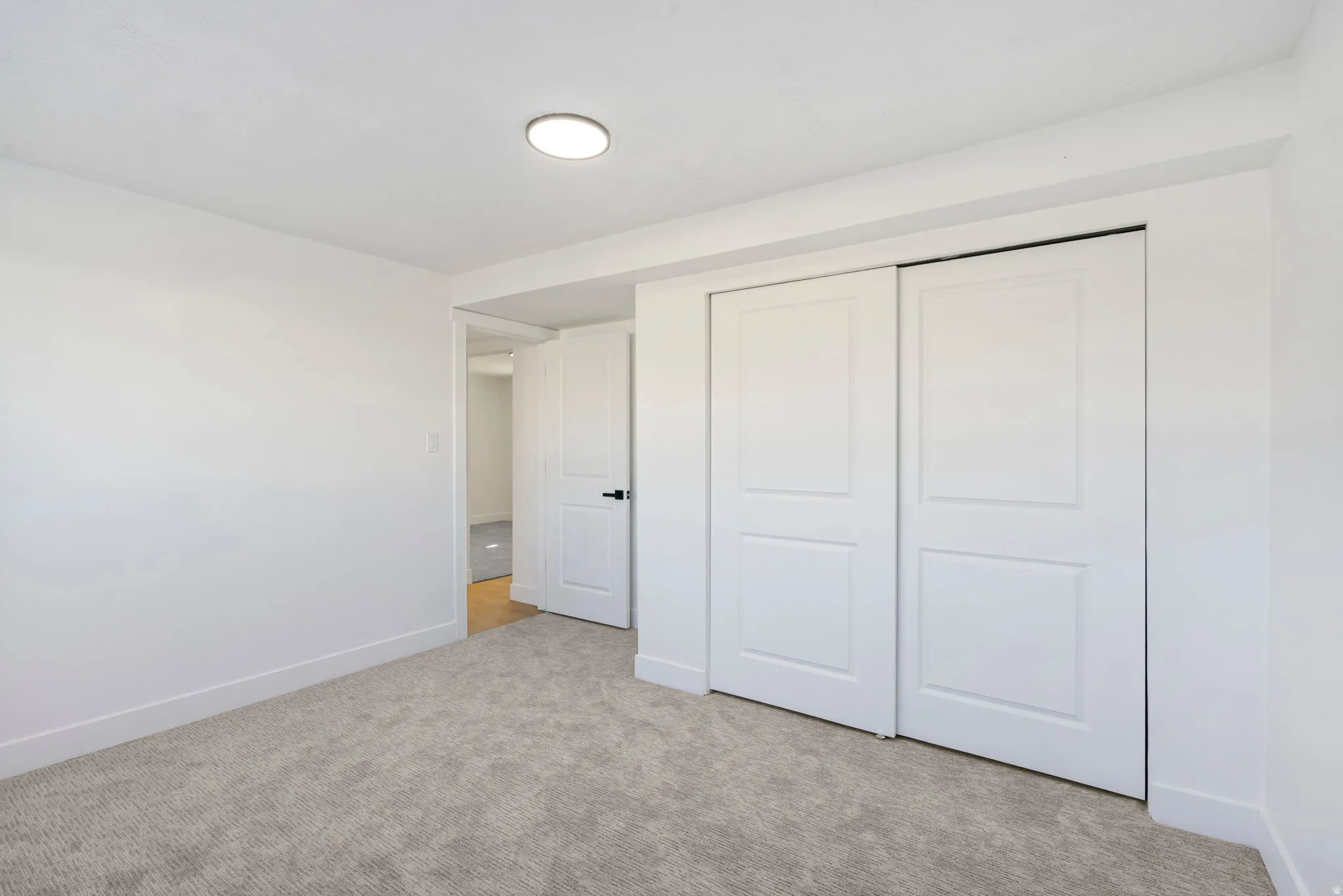 Unfurnished bedroom featuring a closet and light colored carpet