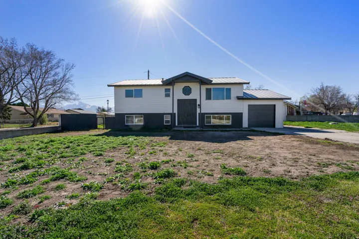 Bi-level home featuring an attached garage, driveway, and a standing seam roof