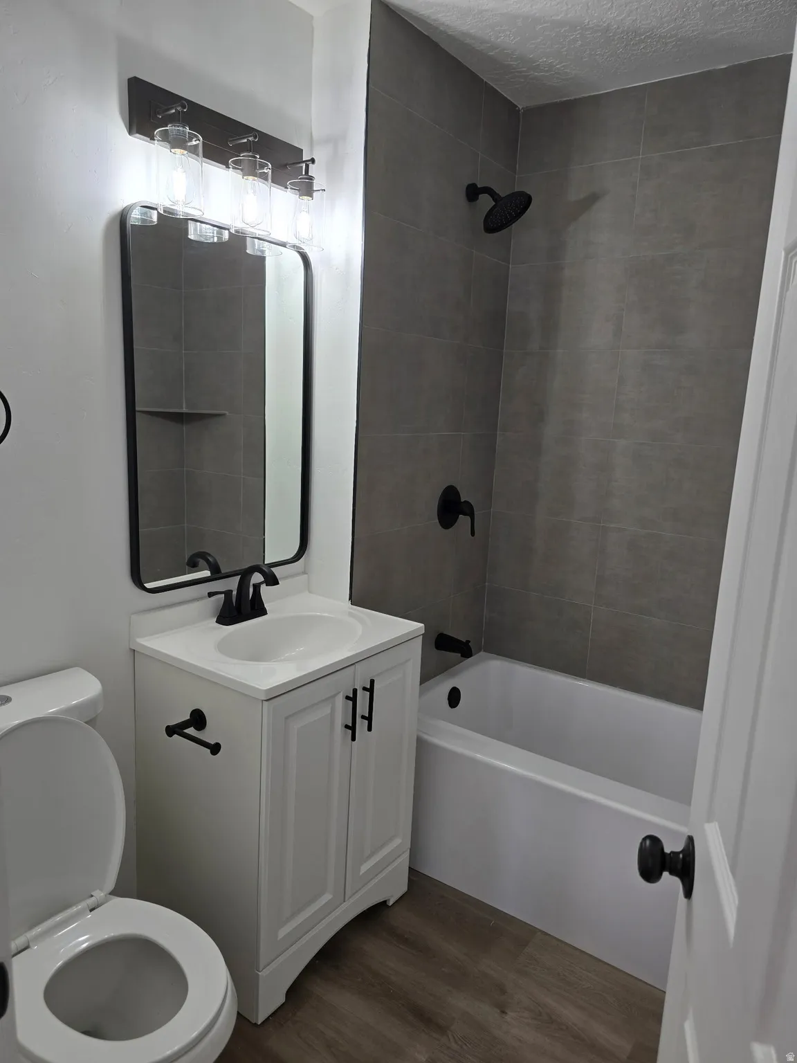 Full bath featuring vanity, dark wood-style floors, shower / bathtub combination, and a textured ceiling