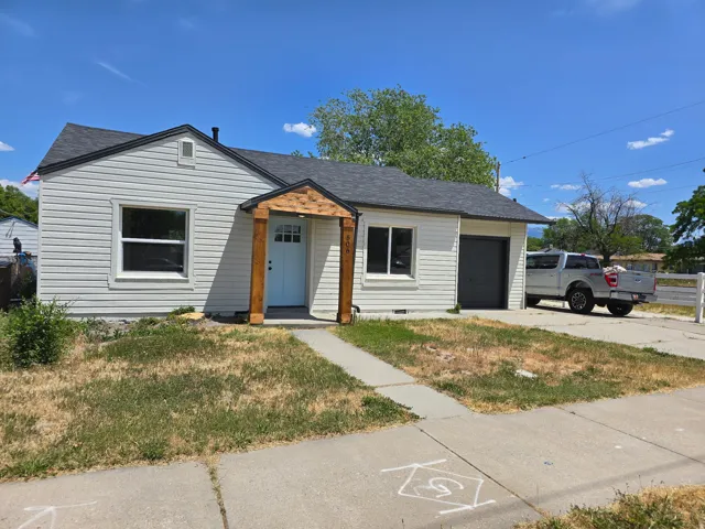 View of front of home featuring roof with shingles, a front yard, a garage, and driveway
