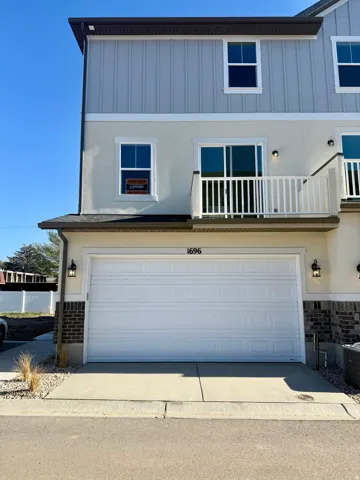 Traditional-style home with a garage, board and batten siding, concrete driveway, and a balcony
