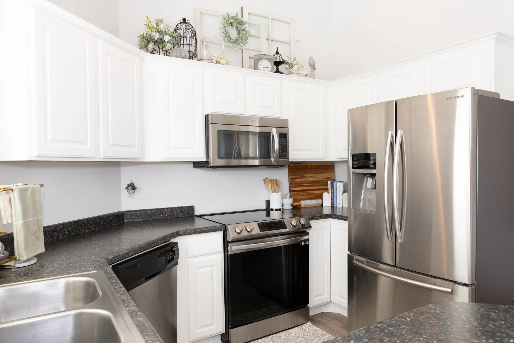 Kitchen featuring dark countertops, stainless steel appliances, and white cabinets