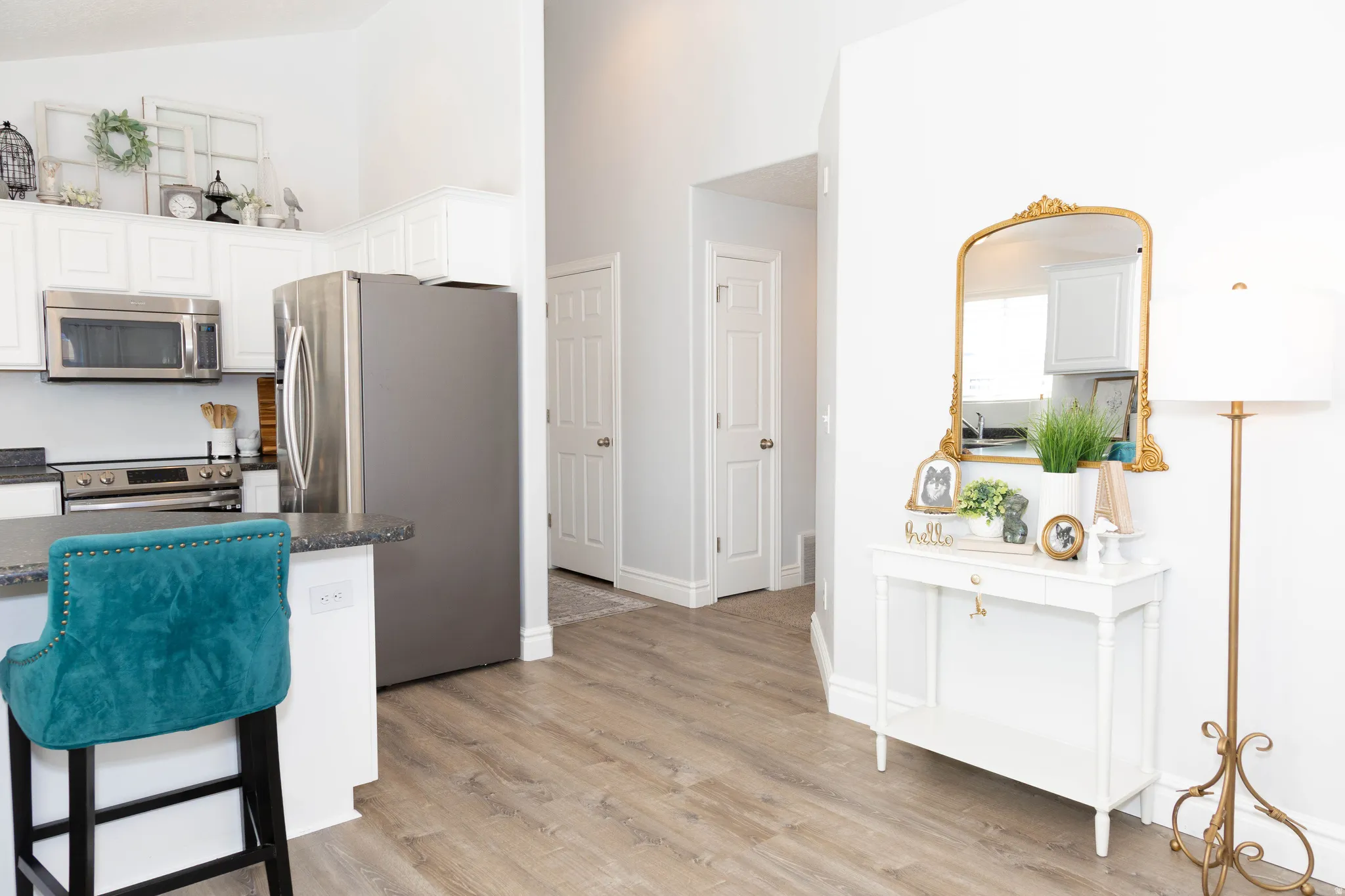 Kitchen featuring stainless steel appliances, white cabinets, light wood-style floors, a breakfast bar, and lofted ceiling