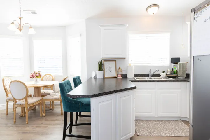 Kitchen featuring dark countertops, white cabinets, light wood-style flooring, freestanding refrigerator, and a chandelier