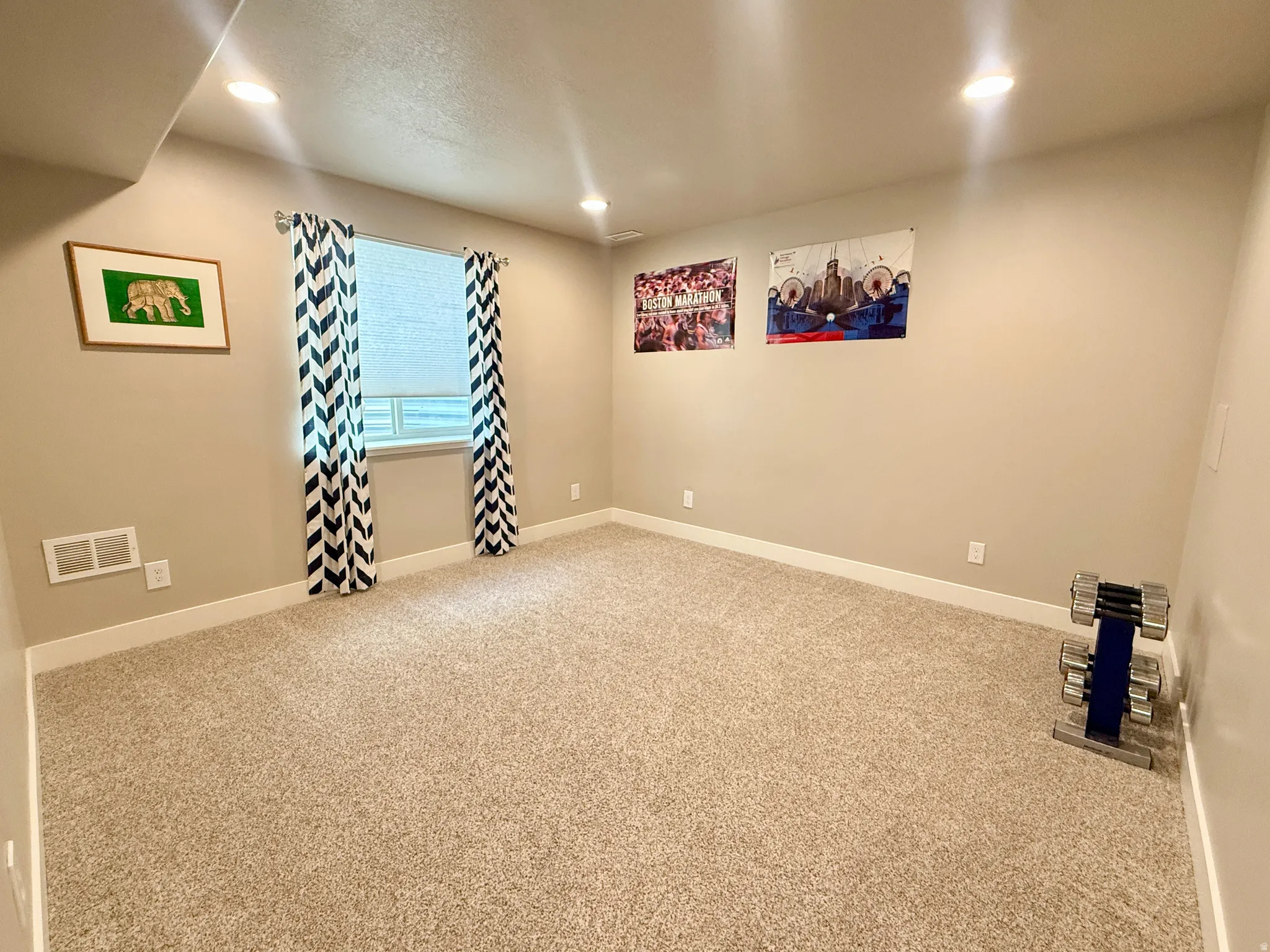 Recessed ceiling lighting, neutral-toned walls, light-colored carpeting, and a single window