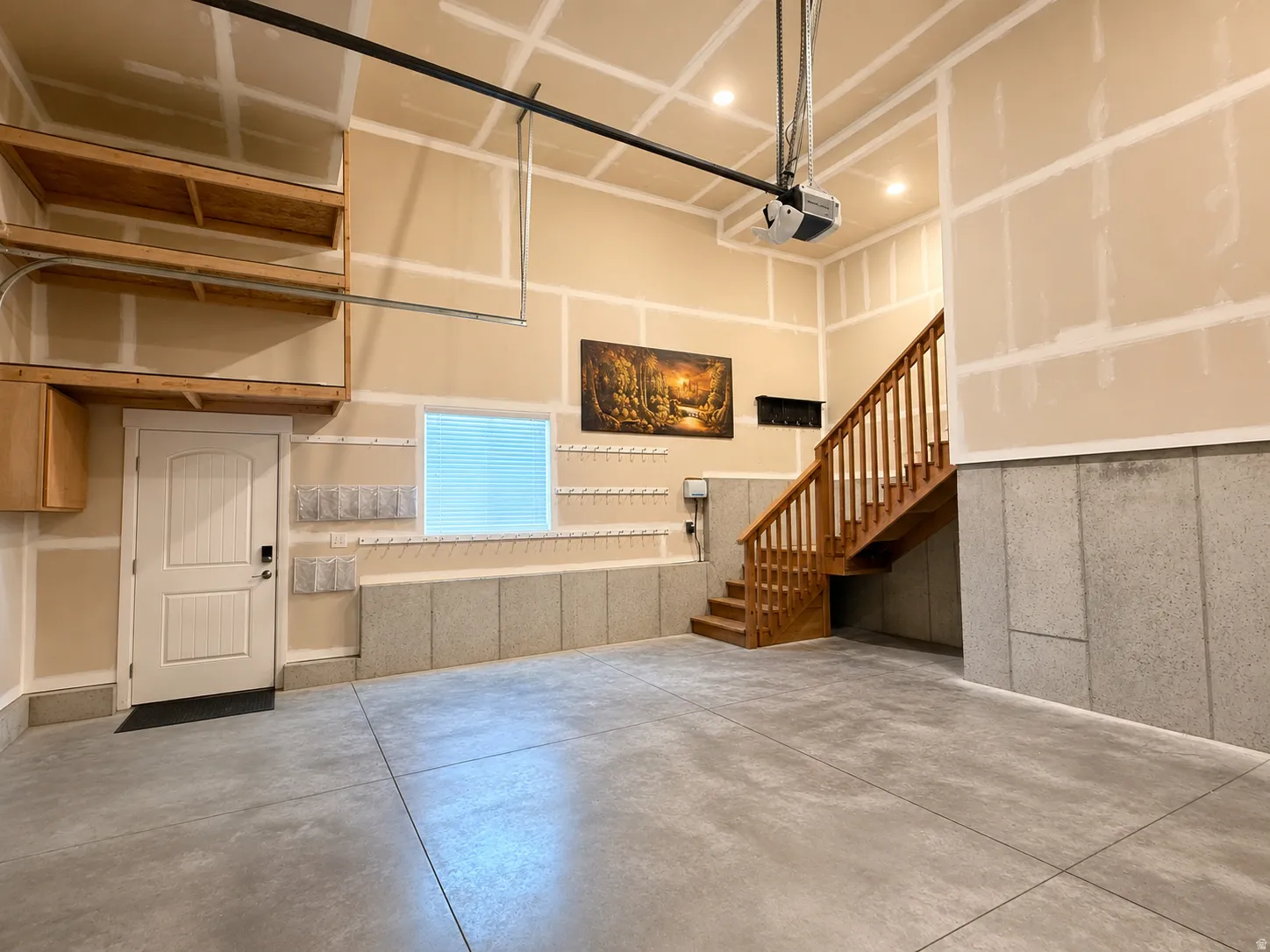 Concrete flooring, wood-finish staircase, built-in overhead shelving, recessed lighting, and a window with blinds