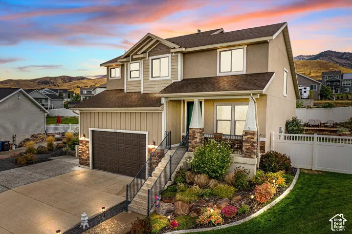 View of front facade featuring a shingled roof, a mountain view, concrete driveway, and board and batten siding