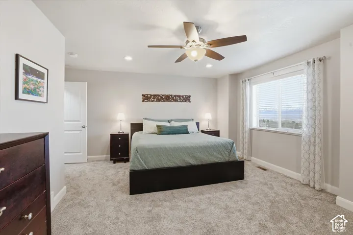 Bedroom featuring light colored carpet, a ceiling fan, and recessed lighting